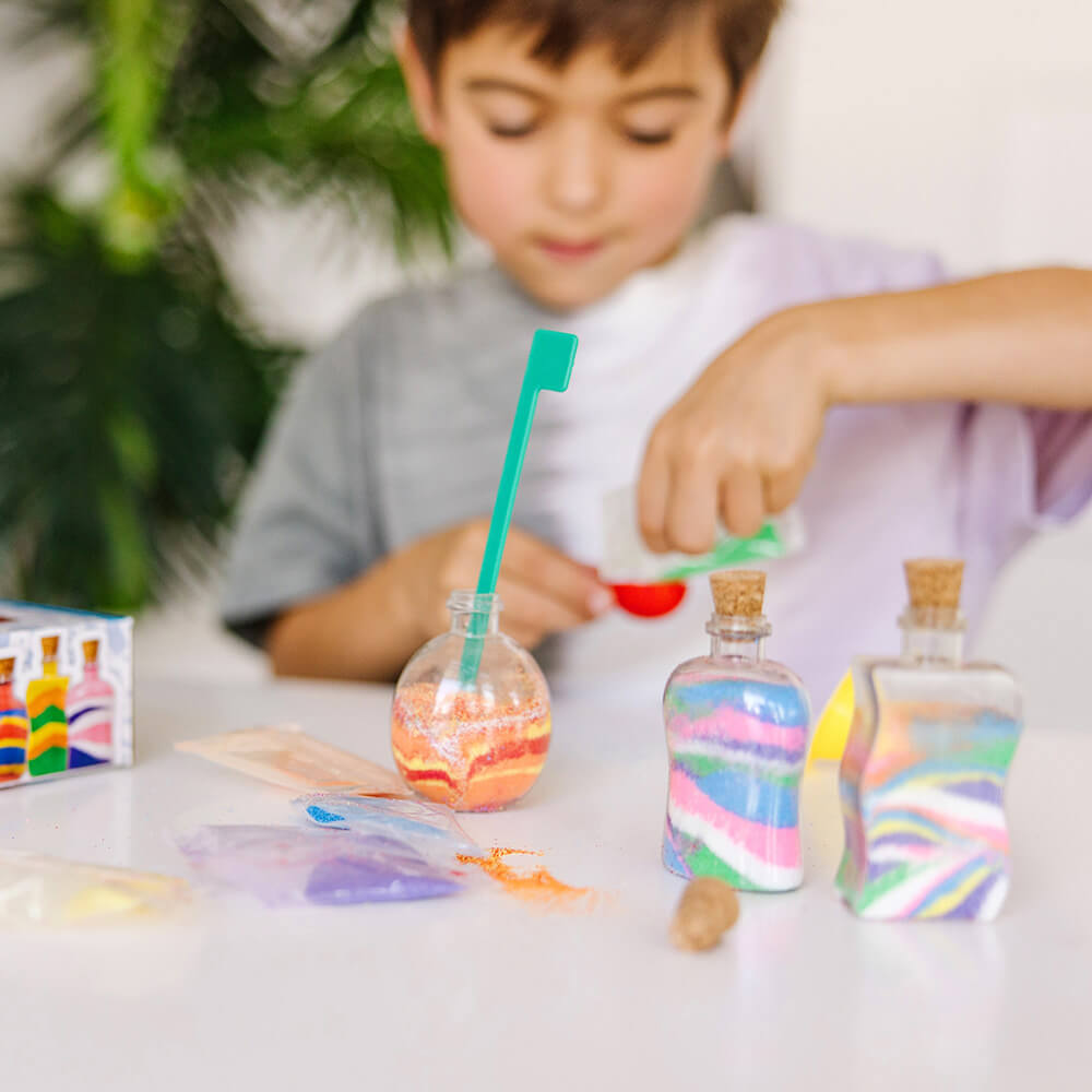 Kid making sand bottles with the Melissa and Doug Created by Me! Sand Art Bottles Craft Kit