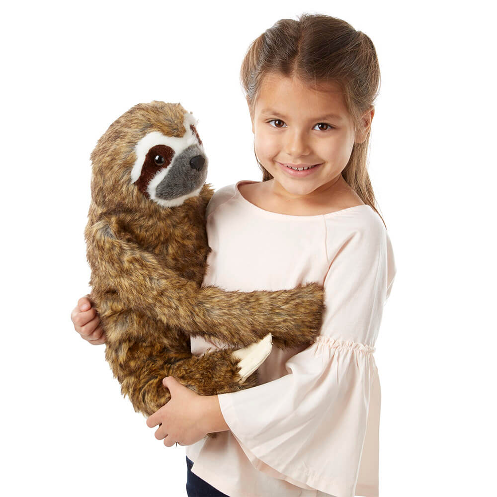 A girl holding Melissa and Doug Lifelike Sloth Plush on her hip and smiling
