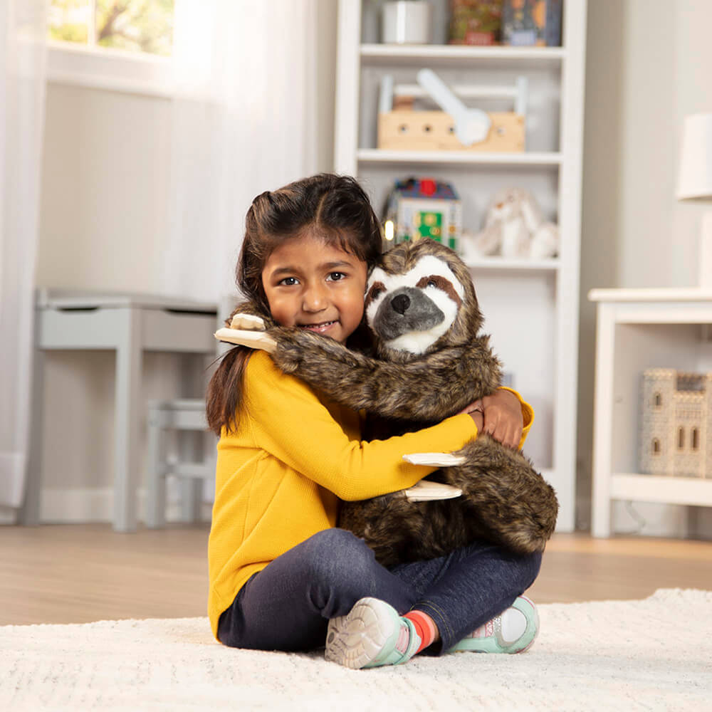 A girl hugging Melissa and Doug Lifelike Sloth Plush