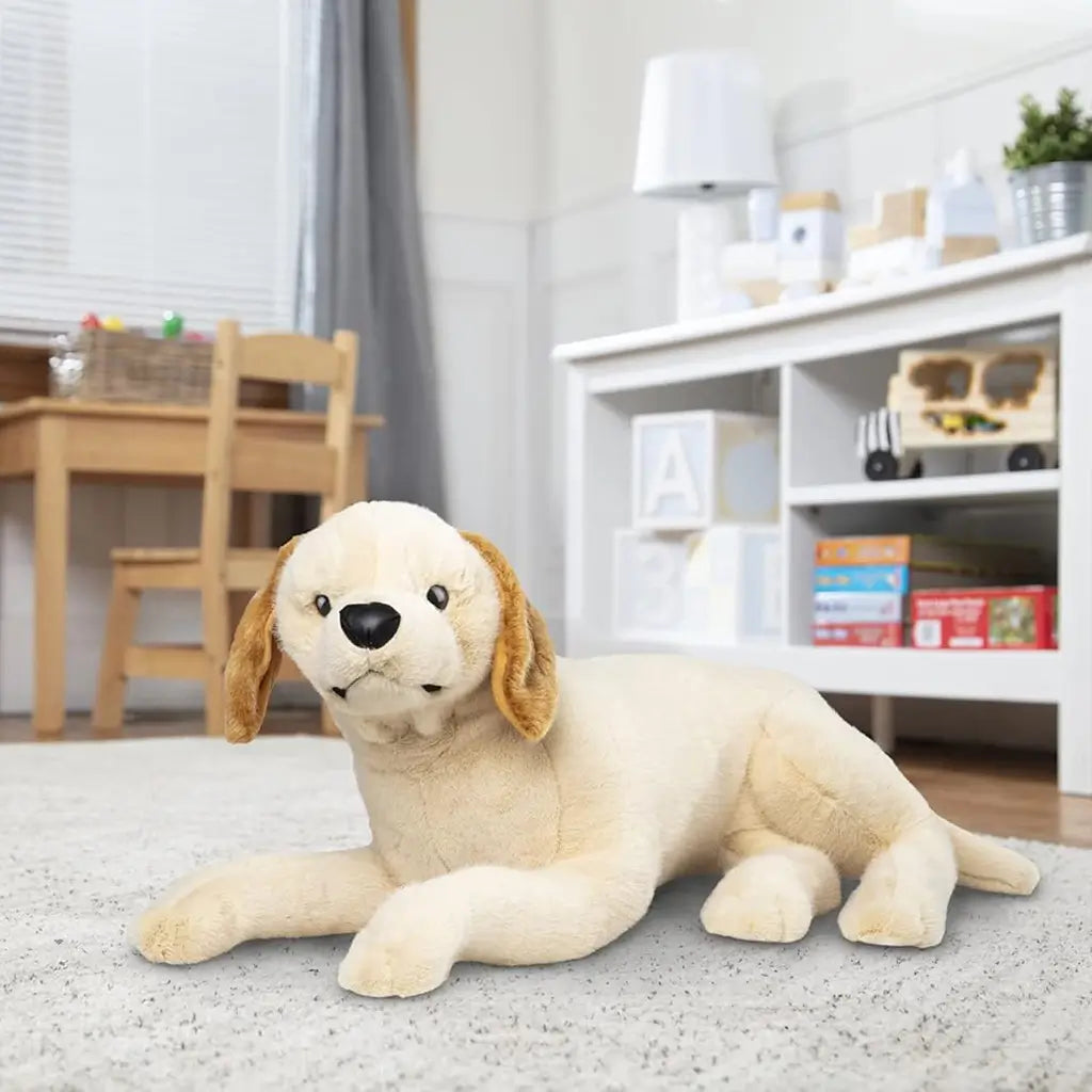 Melissa & Doug lifelike plush yellow Labrador puppy toy in cream fabric with golden brown ears, soft texture, and realistic details, shown lying down as a cuddly companion for kids.
