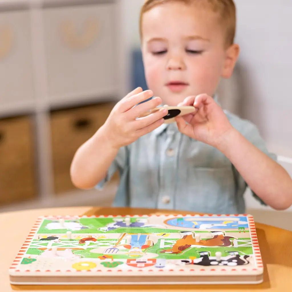 A toddler examines a cow-shaped piece from the Melissa & Doug Old MacDonald’s Farm sound puzzle, promoting cognitive learning and auditory development through interactive play.