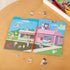 Paw Patrol puffy sticker activity book open on a wooden table, showing colorful cartoon pups, kids, and animals placed on a pink pet shop scene with a bright sunny sky.