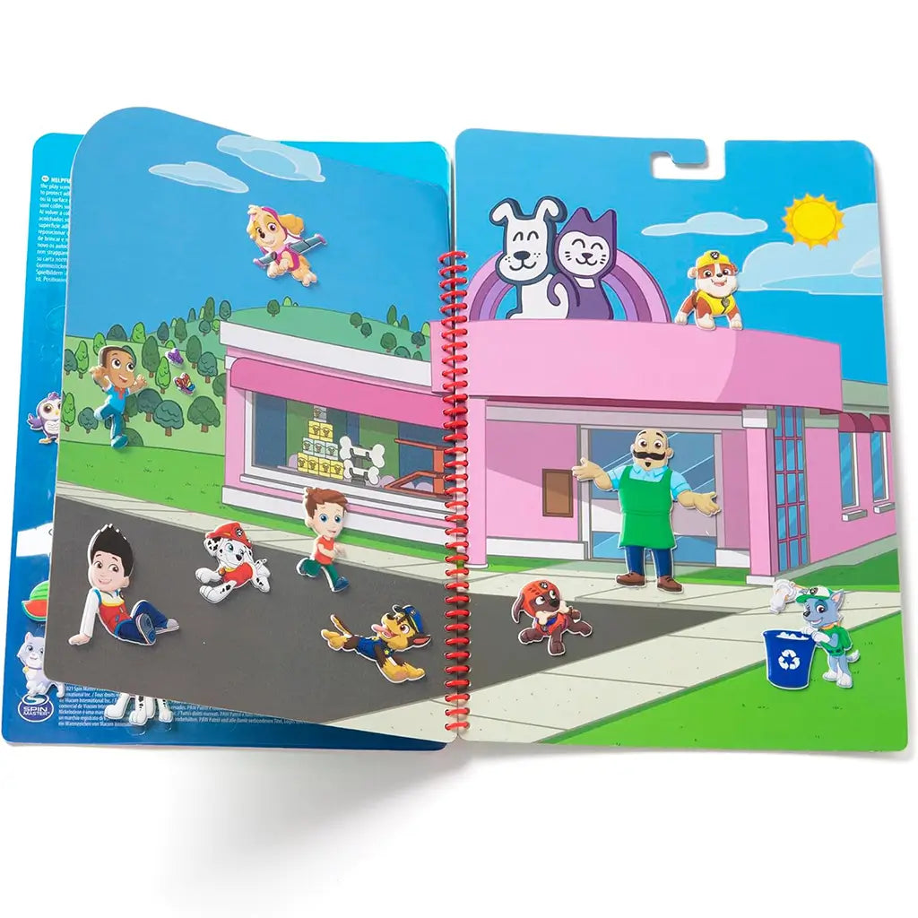 Open Paw Patrol puffy sticker book with characters placed on a bright pet shop scene, featuring a pink building, green grass, and blue skies with a cheerful cartoon shopkeeper.