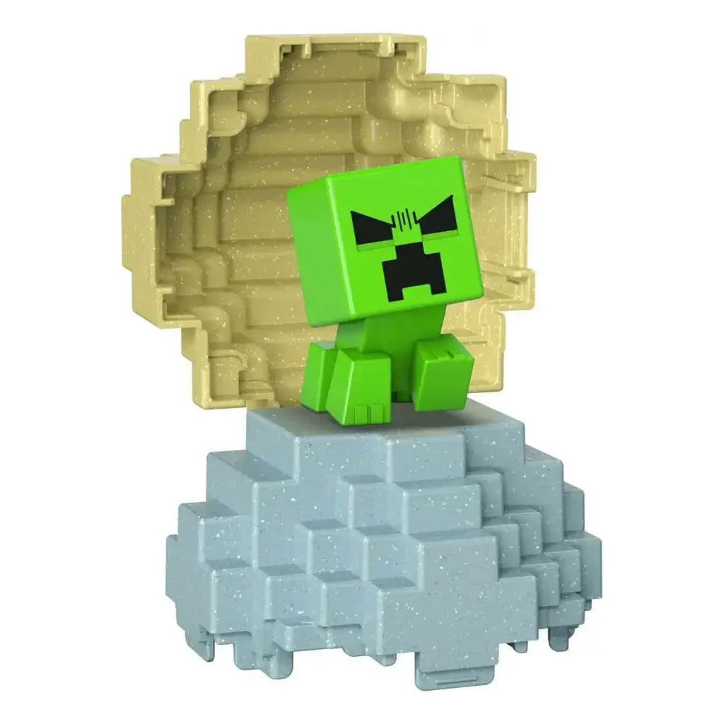 Minecraft Mini Mode Creeper toy posed on an opened blue-and-yellow pixel-style spawn egg, highlighting its collectible design and blocky texture inspired by the video game’s signature aesthetic.