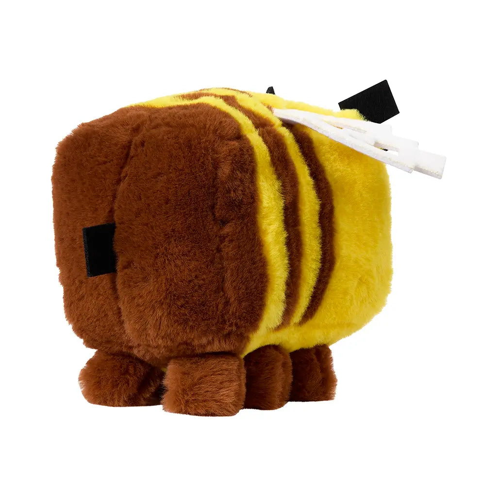 Minecraft bee plush toy in yellow and brown fuzzy fabric with square shape, white pixel-style wings, and small brown legs, shown from angled rear view on plain background.