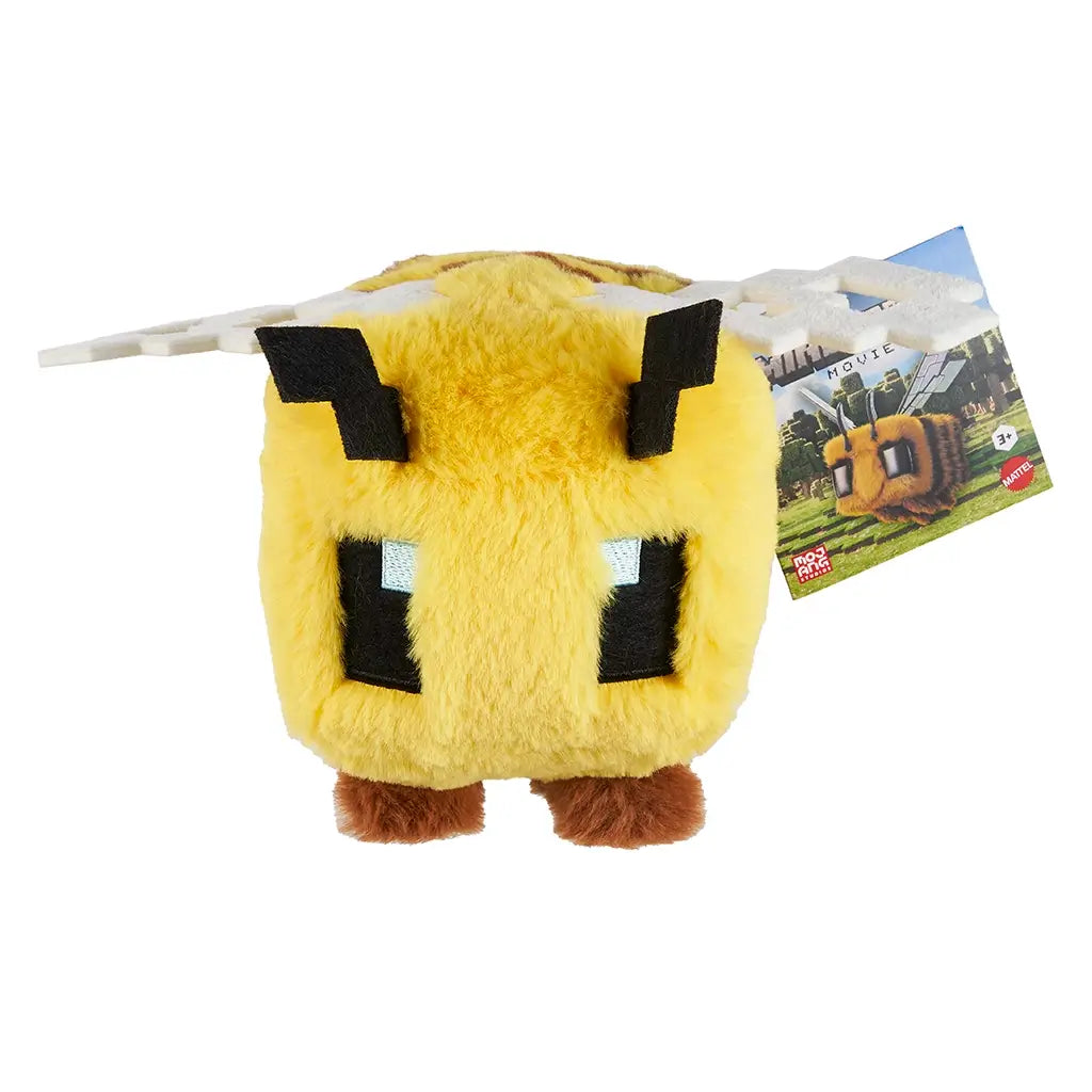 Minecraft bee plush with yellow fur, black pixel eyes, brown legs, and white wings, displayed with attached product tag featuring game artwork in front view.