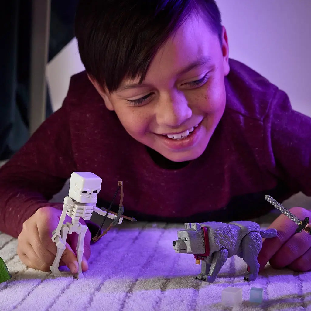 Smiling child in maroon shirt playing on carpet with Minecraft Movie Skeleton figure holding a bow, interacting with gray wolf toy under soft purple lighting.