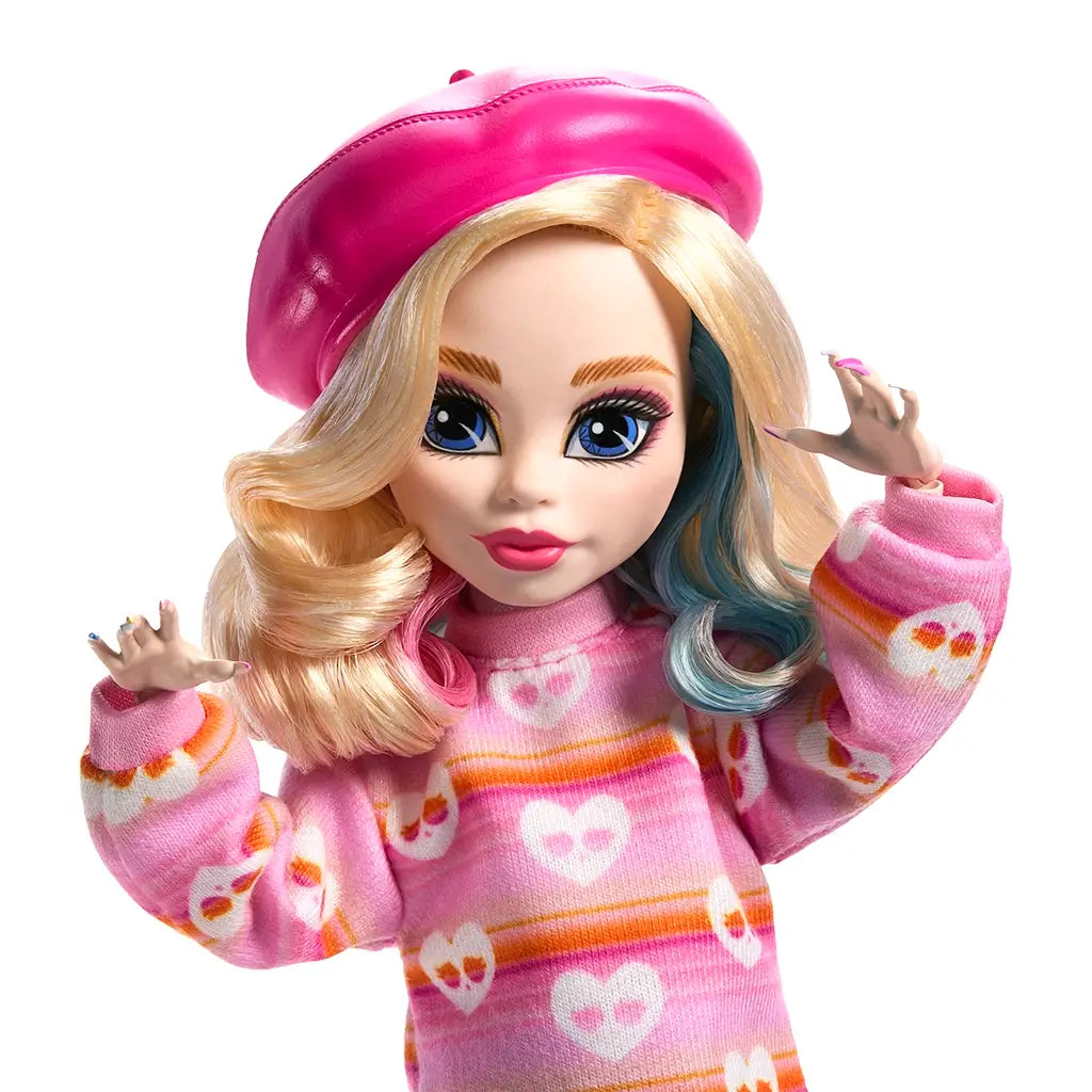 Close-up of Monster High Enid Sinclair doll with blonde curls, pink beret, and streak of blue hair, wearing pink heart-print sweater and showing detailed face paint design.