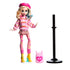 Monster High Enid Sinclair doll in pink heart-pattern sweater, plaid skirt, and yellow boots, posed with pink backpack and black display stand against white background.