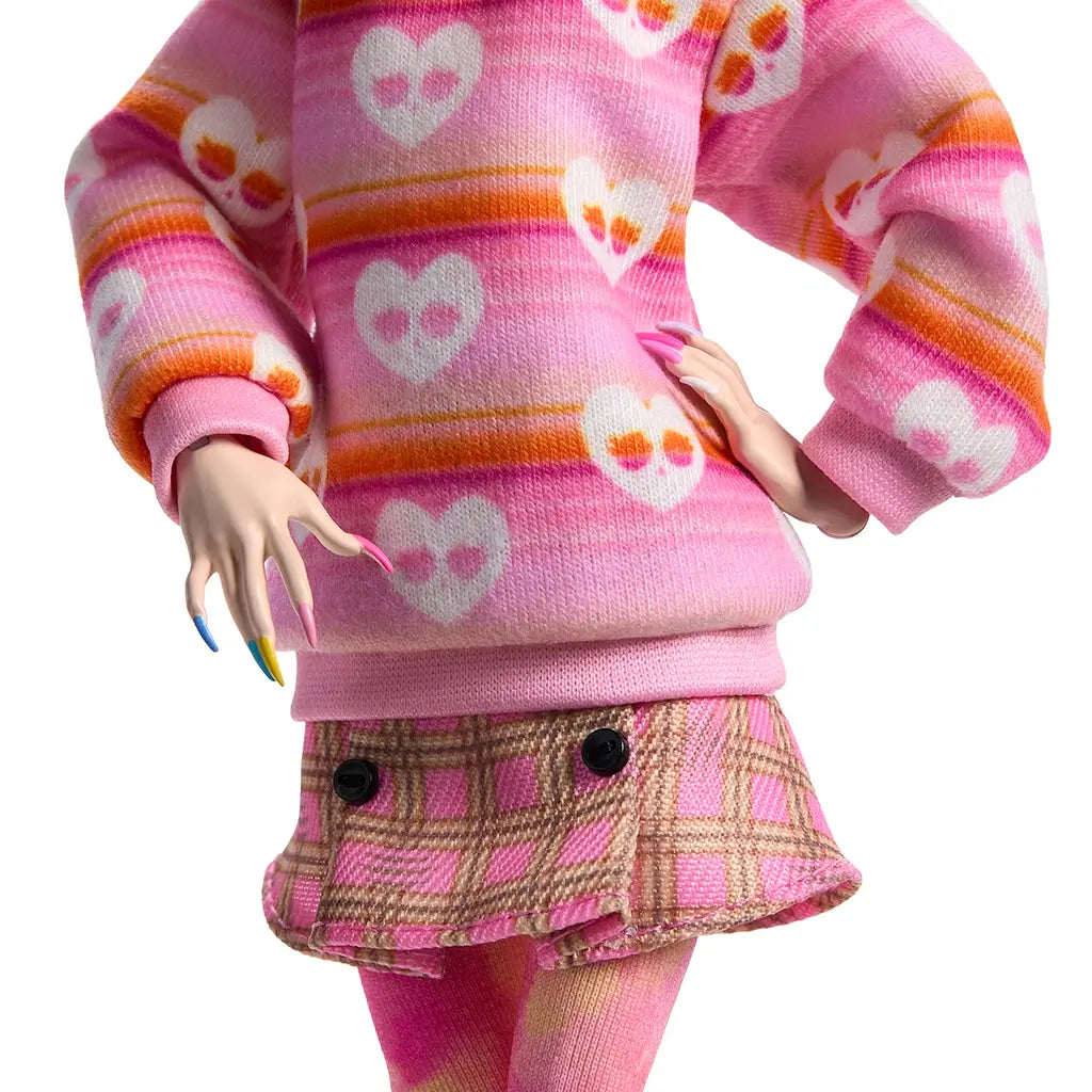 Close-up of Monster High Enid Sinclair doll outfit showing pink heart-print sweater, plaid pink skirt with button accents, and multicolor manicured nails for stylish detailing.