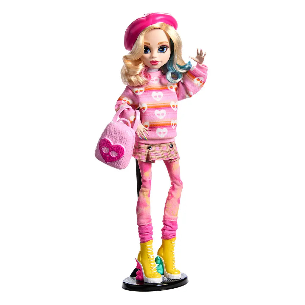 Monster High Enid Sinclair doll styled in a pink beret, heart-print sweater, plaid skirt, and yellow boots, posed with matching pink backpack accessory on display stand.