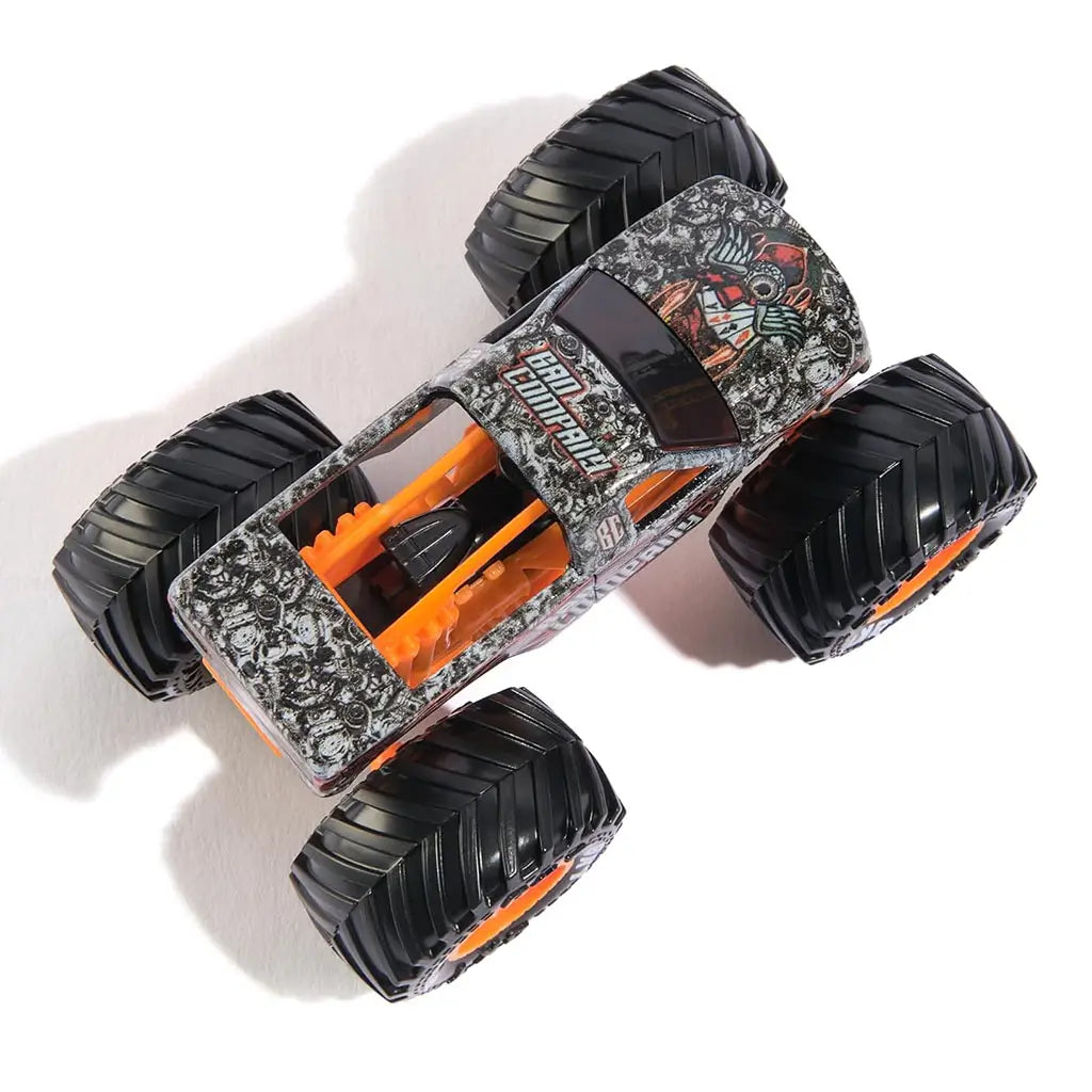 Top view of Monster Jam Bad Company diecast truck, highlighting intricate black-and-white skull pattern, orange undercarriage, and four massive tread tires.
