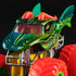 Closeup of Monster Jam Dragon 1:64 scale diecast truck, showing green dragon face design with yellow accents, red horns, sharp teeth, and oversized neon red wheels.