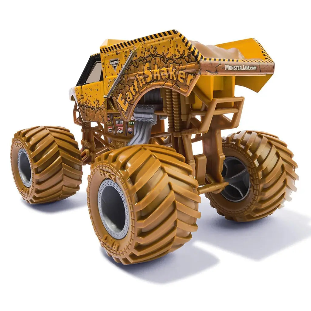 Rear angled view of Monster Jam Earth Shaker diecast truck highlights bold yellow cracked rock paint, large sculpted dirt bed, thick tread wheels, and authentic suspension build.