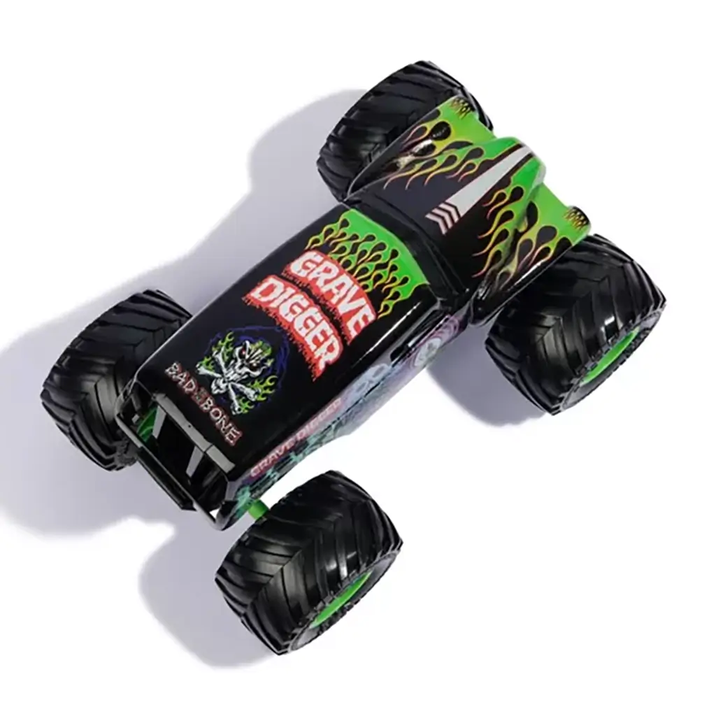 Top view of Monster Jam Grave Digger diecast truck, featuring bold green flames, skull artwork, and red “Grave Digger” lettering across the black roof design.