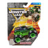 Monster Jam Grave Digger toy truck in black and green painted metal and plastic with flame and skull graphics, boxy body and oversized rubber tires with green rims, sealed in retail blister packaging with action artwork background.