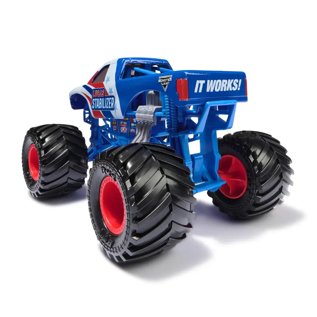 Rear angled view of the Monster Jam Lucas Stabilizer diecast truck shows bright blue frame, black BKT tires with red hubs, chrome exhaust pipes, and bold “It Works!” text on the tailgate.