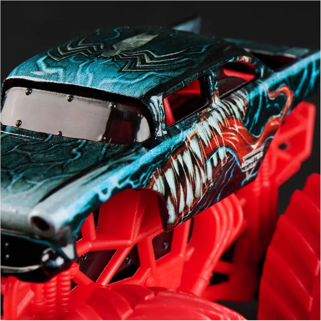 Close-up of Monster Jam Marvel Venom truck highlights black roof with white spider symbol and vivid side artwork of snarling fangs over a bright red plastic frame.