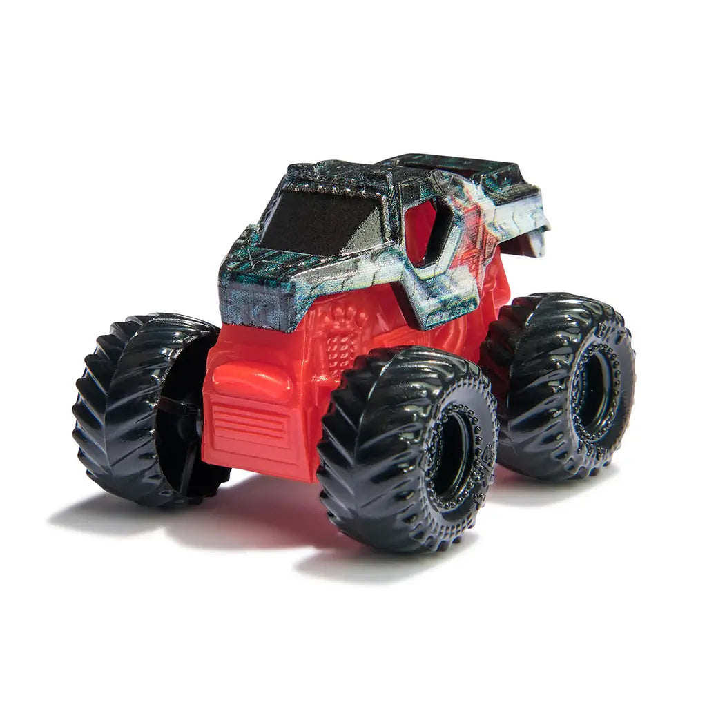 Monster Jam Winter Soldier mini truck in red and dark metallic plastic with black oversized wheels, compact rugged monster truck shape for play, displayed on a simple white studio background.