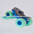 Monster Jam Son-uva Digger toy truck in black and teal plastic with mud texture, large green tires and blue rims, partially submerged in water to show color change feature, set against a clean minimal background