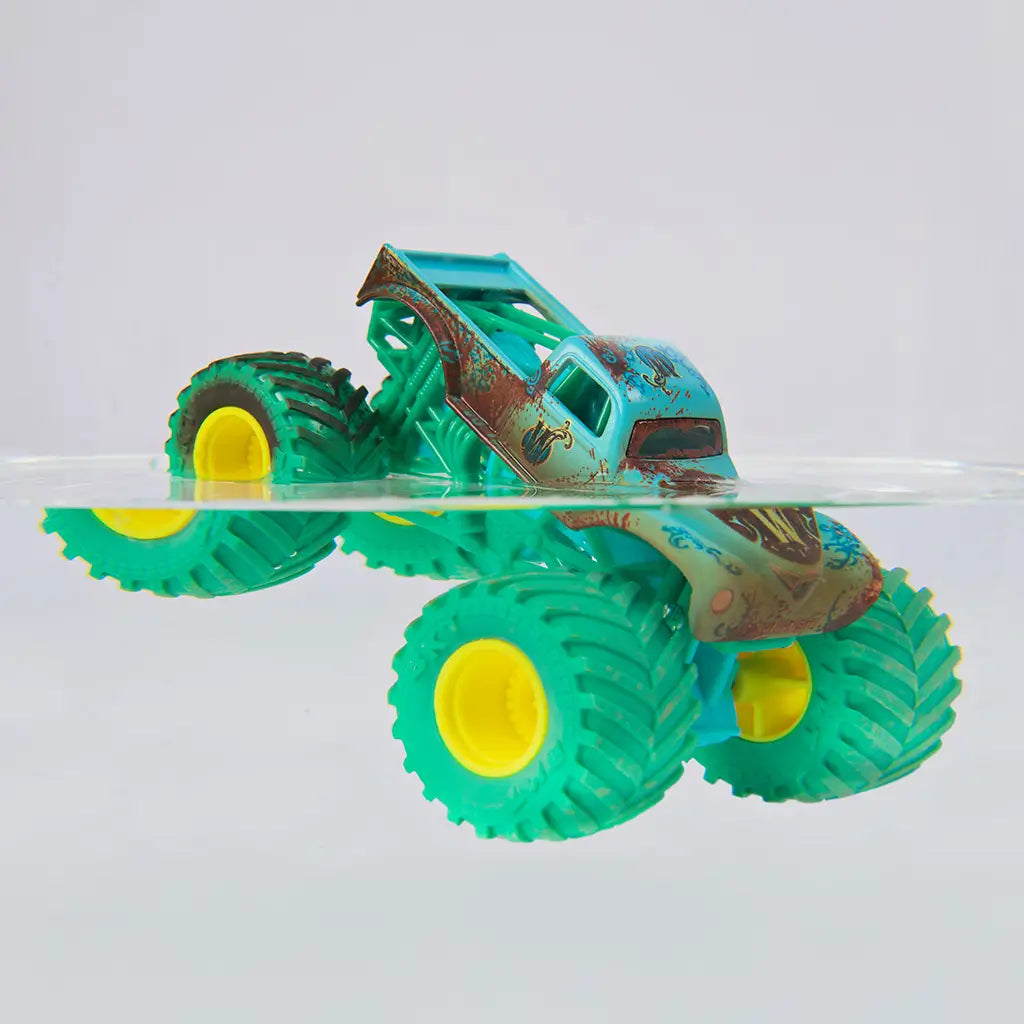 Monster Jam color change toy truck in teal plastic with mud detailing and bright yellow rims, partially submerged in clear water to demonstrate transformation, rugged monster truck form on a minimal background
