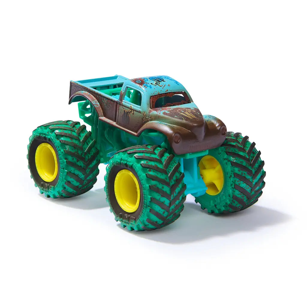 Monster Jam mud blasters toy truck in teal and brown plastic with dirt effect texture, oversized green tires and yellow rims, compact monster truck form for play, isolated on a clean white background