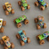 Monster Jam toy trucks in mixed bright colors with plastic bodies, thick rubber tires, and rectangular forms, arranged in a scattered top view layout on a smooth neutral tabletop for collectible display.