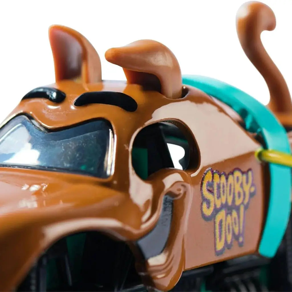 Closeup of Monster Jam Scooby-Doo truck showing sculpted dog ears, raised eyebrows, detailed face with playful expression, and side logo branding in bright yellow and purple lettering.