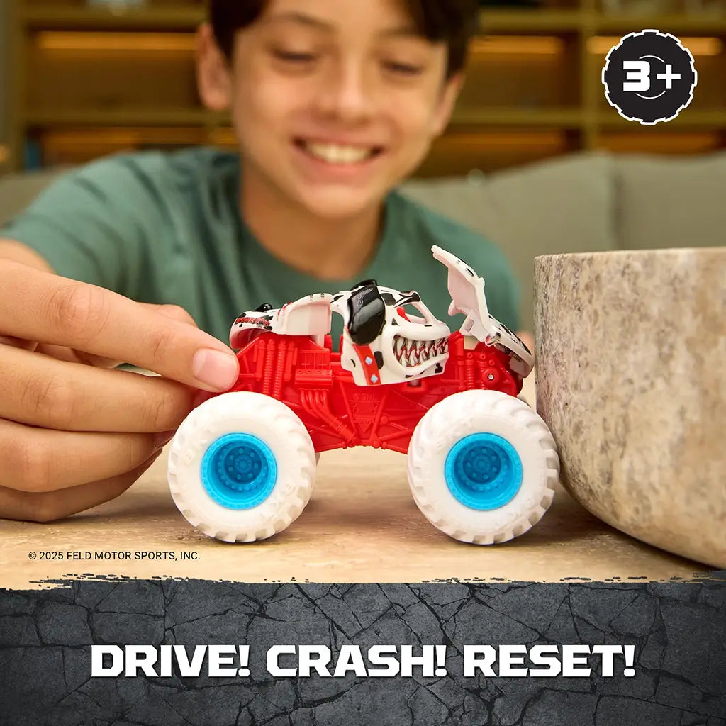 Monster Jam Monster Mutt Dalmatian toy truck red plastic body with white spotted dog shell and blue wheels being pushed forward by a child to drive, crash, and reset on a tabletop setting