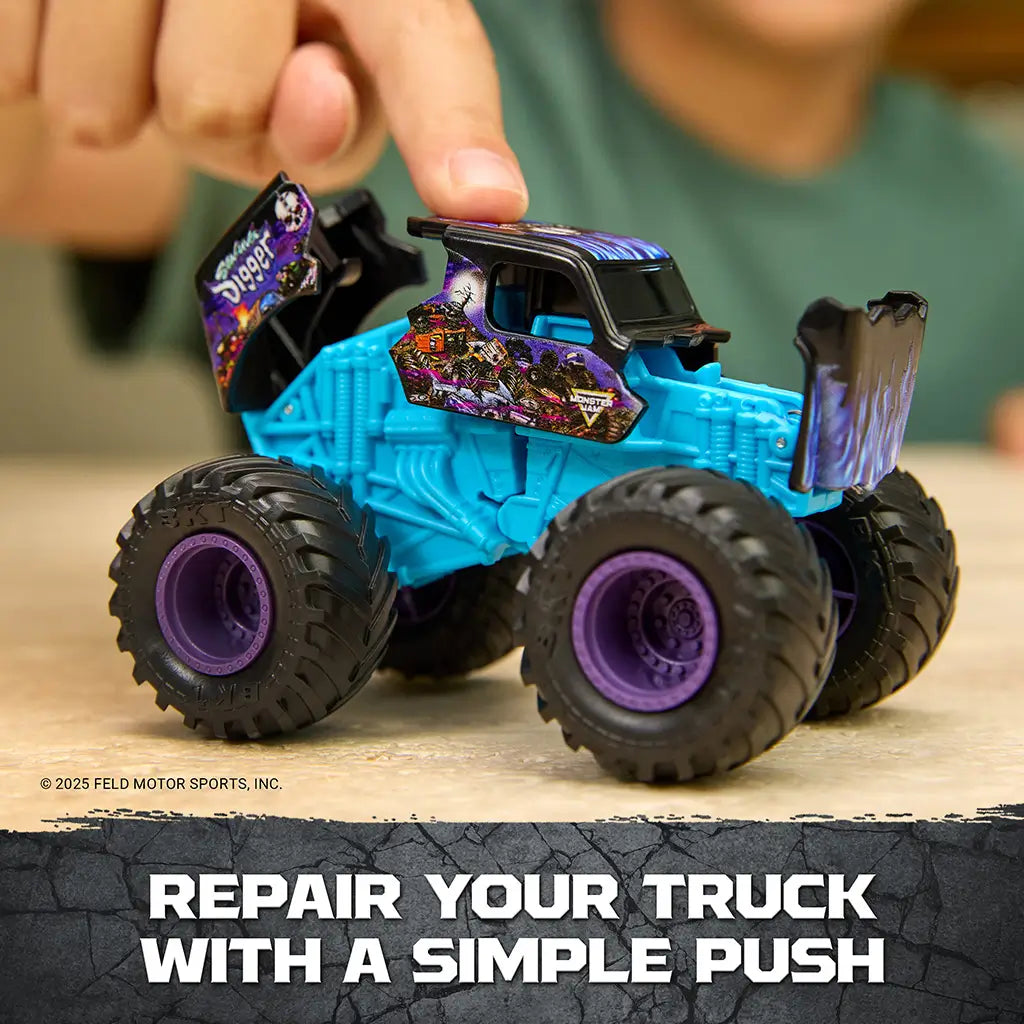 Monster Jam Son Uva Digger toy truck in teal blue plastic with black body and purple wheels, rugged monster truck shape, shown being pressed to repair parts on a tabletop indoor setting.