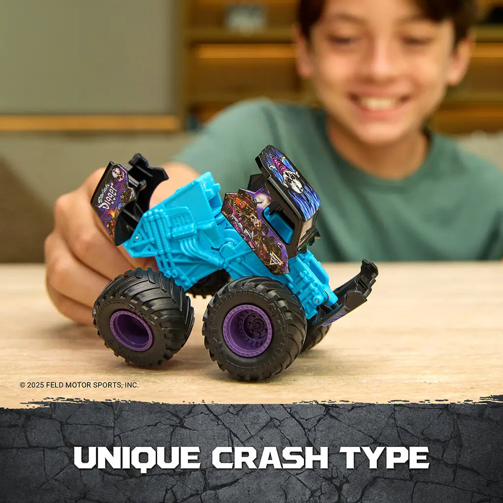 Monster Jam Son Uva Digger toy truck in teal blue plastic with black and purple details, rugged monster truck form with movable parts, shown bent in crash position on a tabletop indoor background.