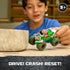 Monster Jam Zombie toy truck in green plastic with gray and red accents, oversized monster truck form, shown mid-play by a child demonstrating drive crash reset feature on a tabletop indoor setting.