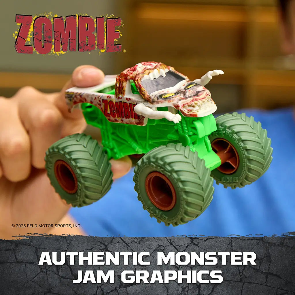 Monster Jam Zombie toy truck in green plastic with gray decayed body and red accents, detailed monster truck shape with zombie graphics, held in hand highlighting themed design indoors.