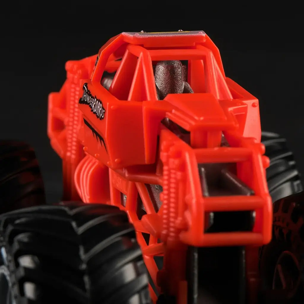 Closeup of Monster Jam ThunderROARus 1:64 scale truck front section, highlighting red frame, black tires, silver detailing, and angular cage body style.