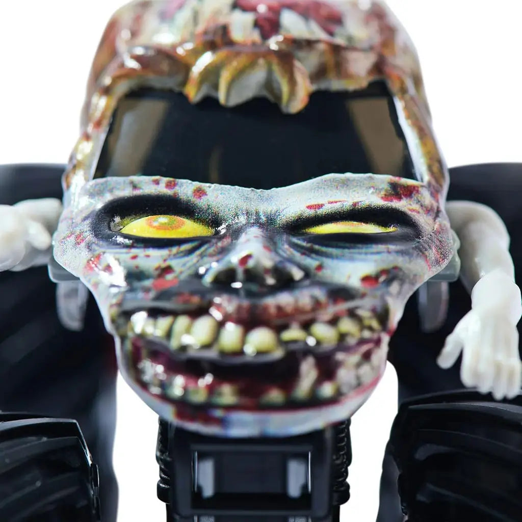 Closeup of Monster Jam Zombie toy truck front with grotesque molded zombie face, yellow eyes, bloody details, and extended arms, emphasizing the horror-themed collectible design.