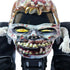 Closeup of Monster Jam Zombie toy truck front with grotesque molded zombie face, yellow eyes, bloody details, and extended arms, emphasizing the horror-themed collectible design.