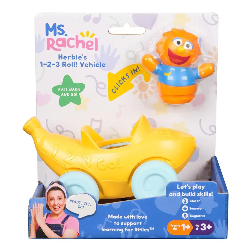 Ms. Rachel Herbie’s 1-2-3 Roll vehicle toy in bright yellow plastic with light blue wheels, banana-shaped car body and smiling figure, pull-back toddler learning car displayed in retail packaging against a pastel music-themed background.
