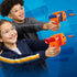 NERF N-Series dart blasters lifestyle image with two smiling kids wearing clear safety glasses, holding orange launchers aimed forward as foam darts fire against a dynamic blue background with motion effects.