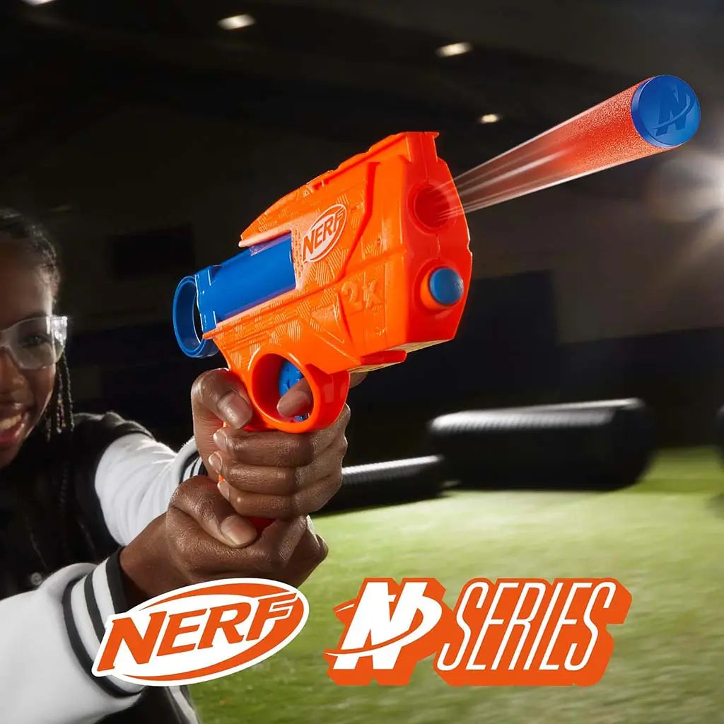 NERF dart blaster is held by a smiling child wearing safety glasses, showcasing the orange-and-blue toy’s textured plastic design and easy trigger grip during active indoor play on a turf field. Described in clear detail for accessibility and user understanding.