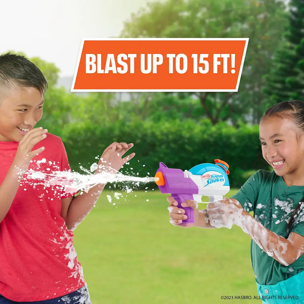 Two smiling kids playing outdoors with the Nerf Super Soaker Foam Fury blaster, spraying foam up to 15 feet, with “Blast Up to 15 Ft!” text shown on a bright orange banner.