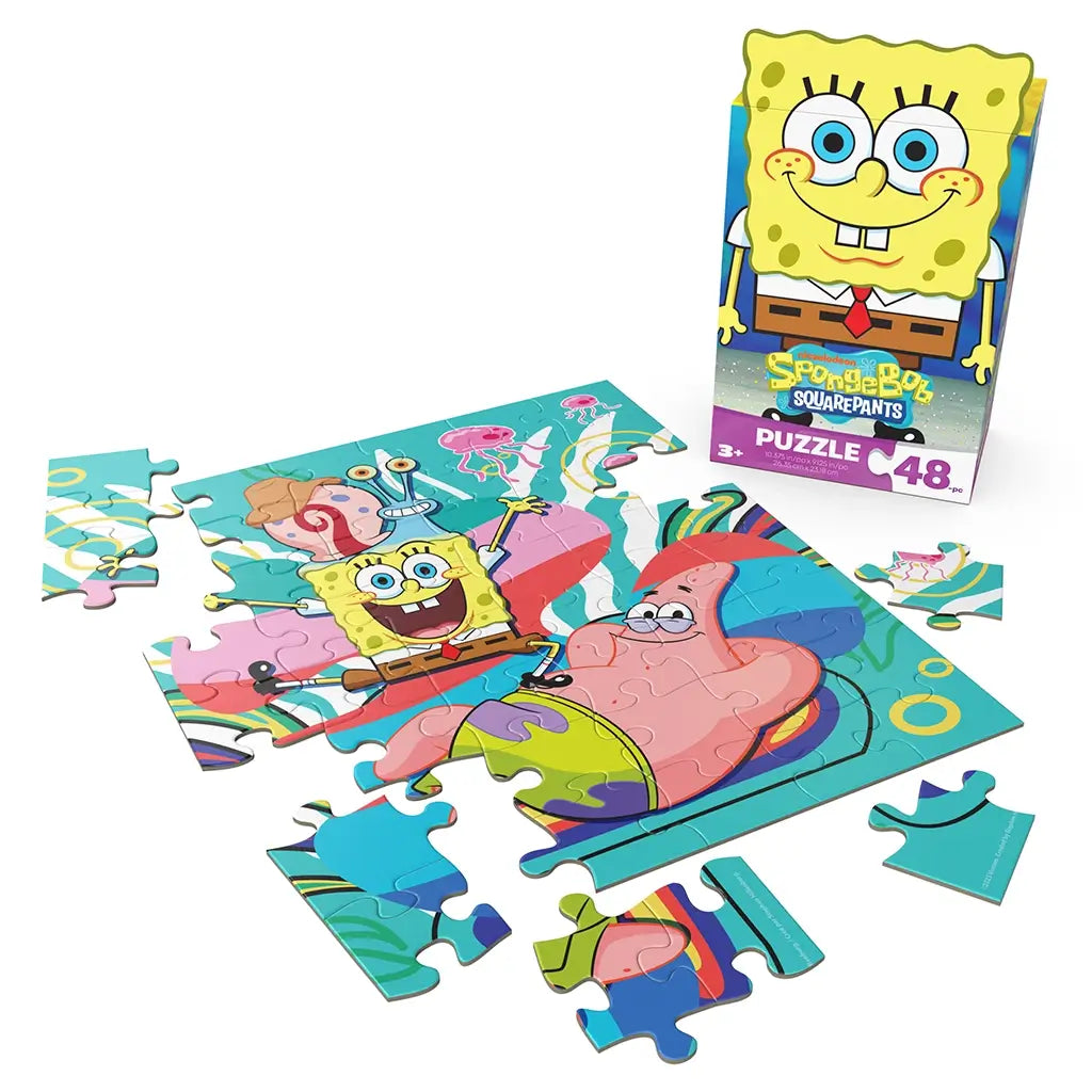 colorful cardboard jigsaw puzzle Nickelodeon SpongeBob SquarePants set, glossy smooth pieces in bright yellow, pink, and blue forming cartoon characters, displayed partially assembled with retail box on a clean white background