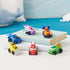 PAW Patrol toy vehicle set in multicolor metal and plastic finishes, compact rounded rescue cars and hovercraft shapes for imaginative play, neatly displayed on stacked books in a light, playful room setting
