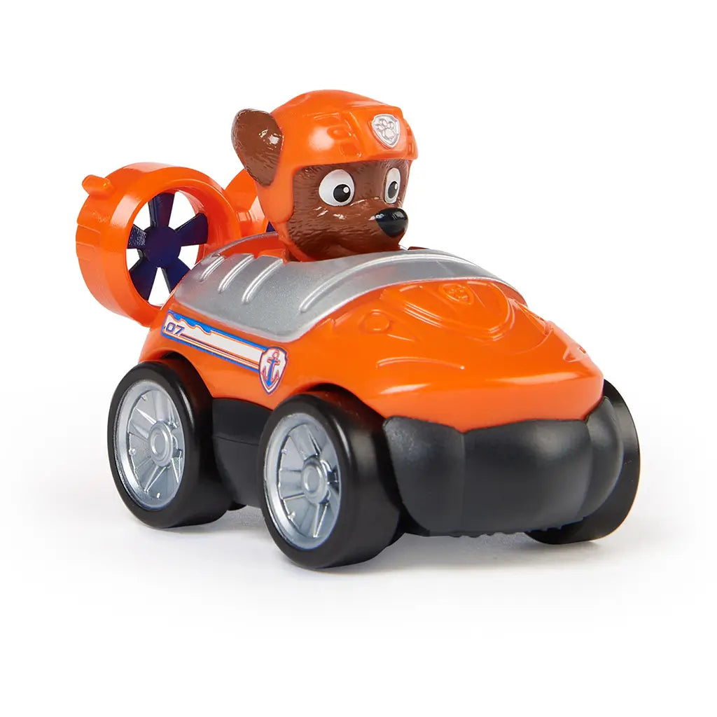 Paw Patrol Zuma racer toy in orange plastic with glossy finish, silver wheels, and brown pup character wearing orange helmet, angled three-quarter view highlighting compact hovercraft design, isolated on a white studio background