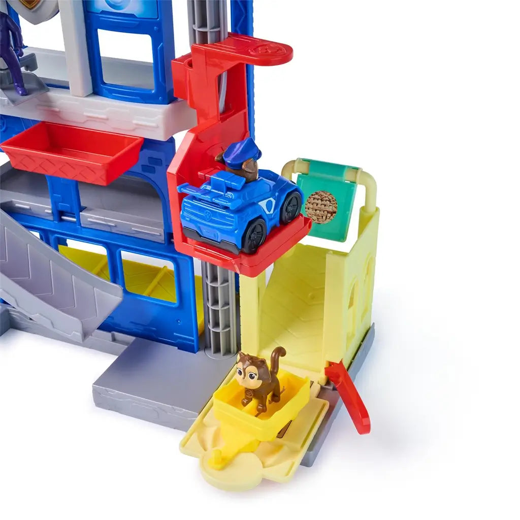 PAW Patrol Pup Squad Search and Rescue HQ playset in blue, gray, and red plastic with multi-level tower, curved ramp and launch platform, interactive rescue headquarters toy shown with vehicle and animal figure on a white background.