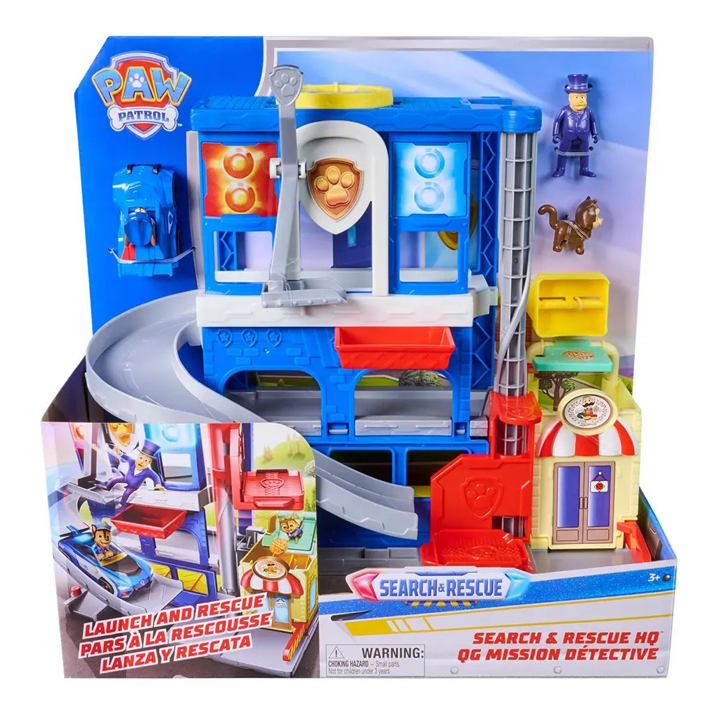 PAW Patrol Pup Squad Search and Rescue HQ playset in blue, gray, and red plastic, multi-level rescue tower with ramp and launch feature, retail packaging front displayed with branding and product images.