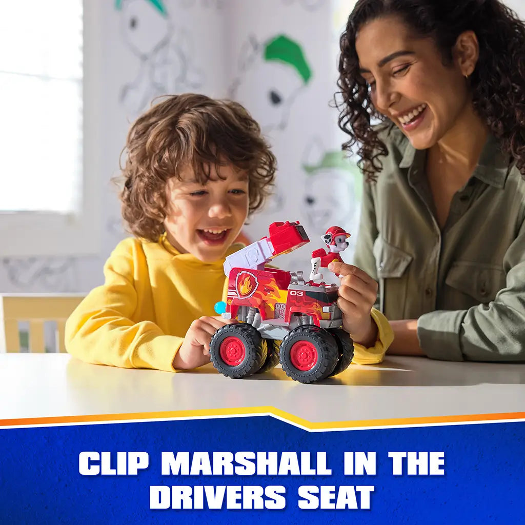 PAW Patrol Marshall fire truck toy shows bright red plastic body with glossy flame details, clip-in driver seat feature, oversized wheels, and ladder, as child and adult interact during playful indoor setting.