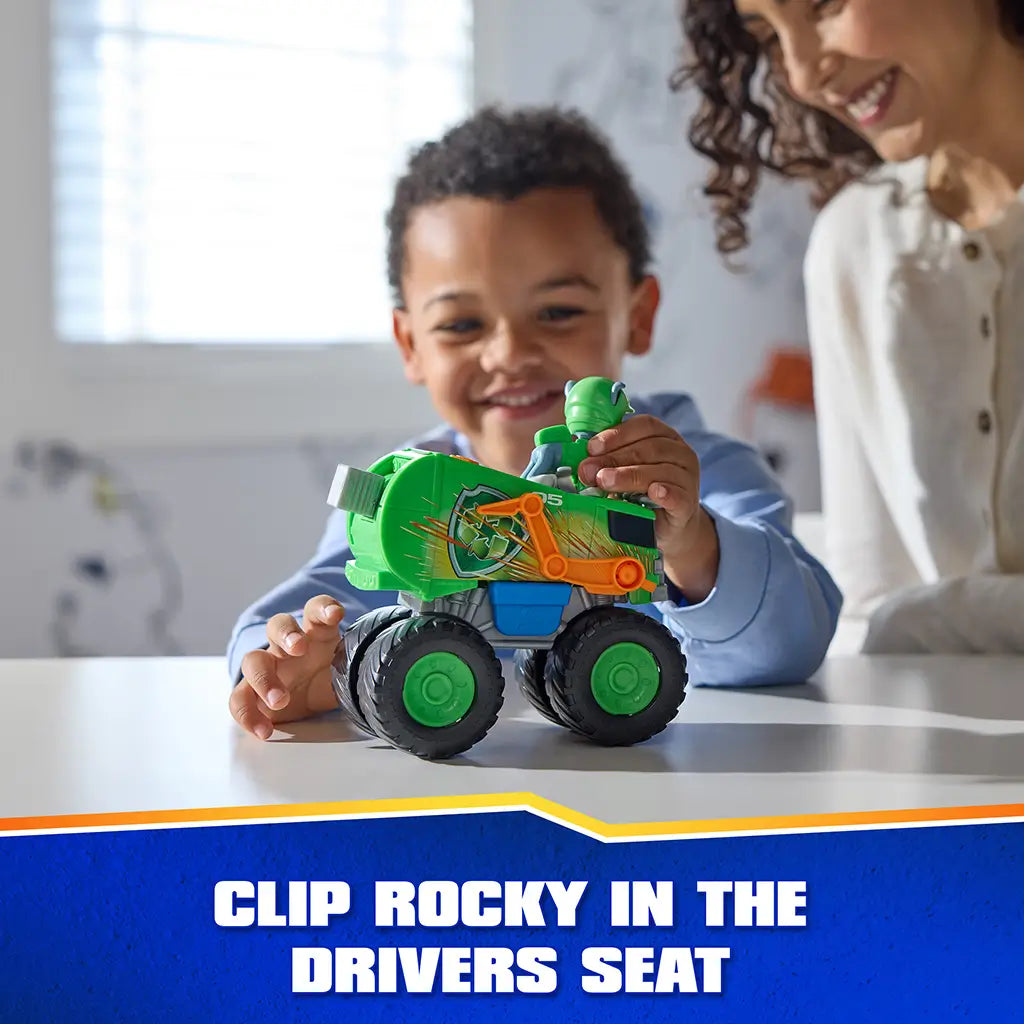 PAW Patrol Rocky recycle truck toy shows bright green plastic body with smooth and textured panels, orange mechanical arm, oversized rugged wheels, and clip-in driver seat feature, used by child and adult indoors.