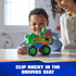 PAW Patrol Rocky recycle truck toy shows bright green plastic body with smooth and textured panels, orange mechanical arm, oversized rugged wheels, and clip-in driver seat feature, used by child and adult indoors.
