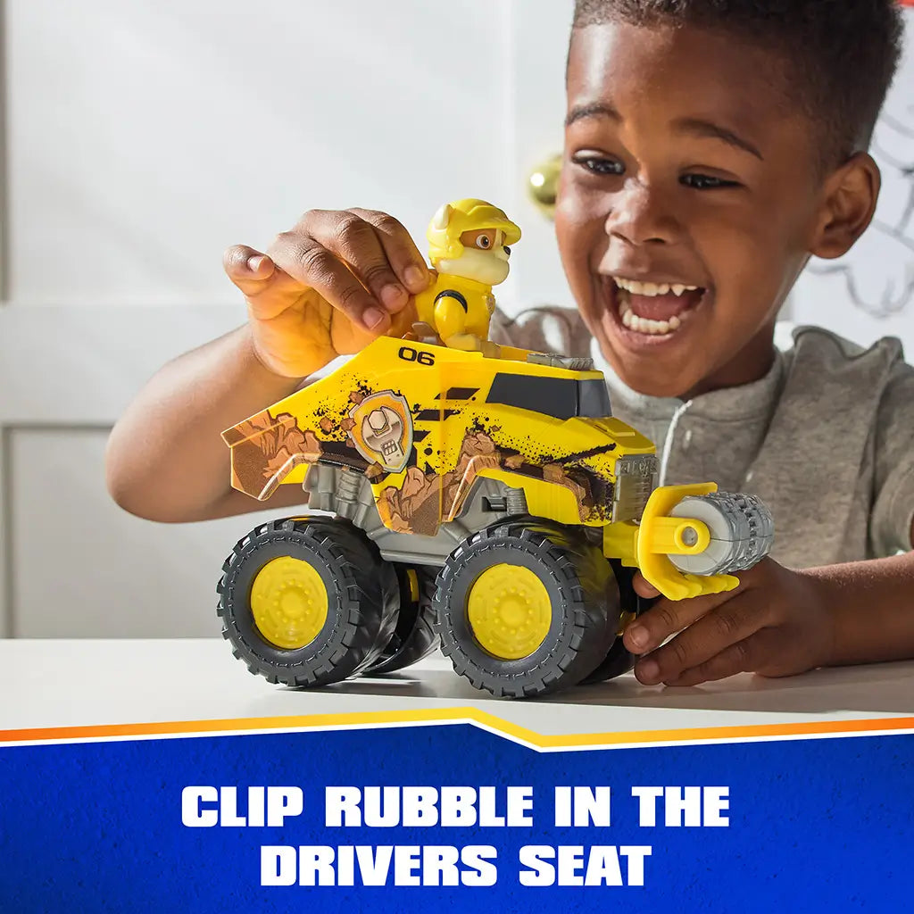 PAW Patrol Rubble bulldozer toy includes bright yellow plastic vehicle with textured mud graphics, large wheels, and removable character figure seated in driver position during interactive play scene.