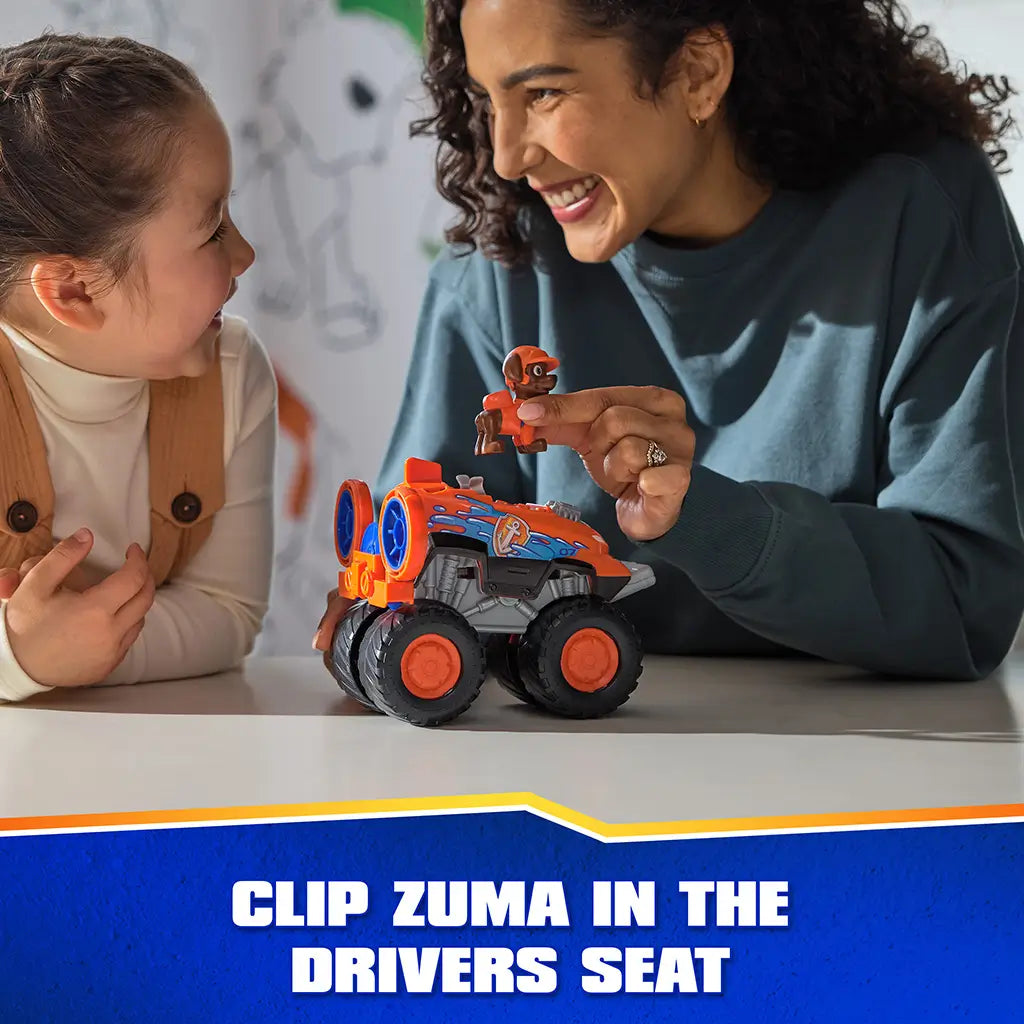 PAW Patrol Zuma hovercraft toy shows bright orange plastic body with smooth and textured panels, chunky oversized wheels, and clip-in driver seat feature, used by child and adult on a tabletop indoor setting.